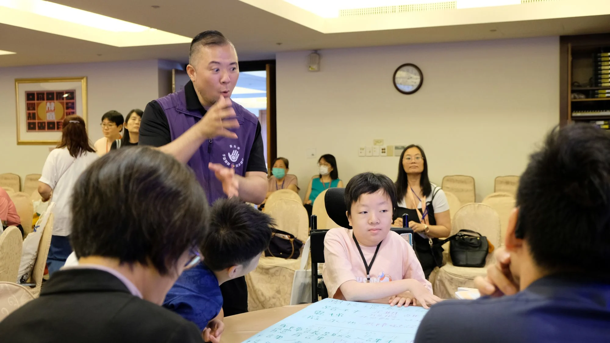 中間身穿粉衣的是 14 歲的桌長林意勳,提到最希望優先改善的一件事,他笑說:「很多事都想改善,但我想要去看電影,希望無障礙座位可以設在後面一點。」攝/曾玉婷